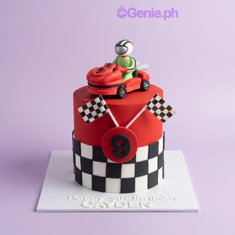 Red 1-tier fondant cake with a race car topper, checkered flags, traffic cones, and a checkered pattern side panel. Red 1-tier fondant cake with a race car topper, checkered flags, traffic cones, and a checkered pattern side panel.