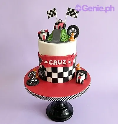 A multi-colored 1 Tier Fondant cake themed Racing Car, with race cars, a podium, number two, checkered patterns, and "CRUZ" text. A multi-colored 1 Tier Fondant cake themed Racing Car, with race cars, a podium, number two, checkered patterns, and "CRUZ" text.