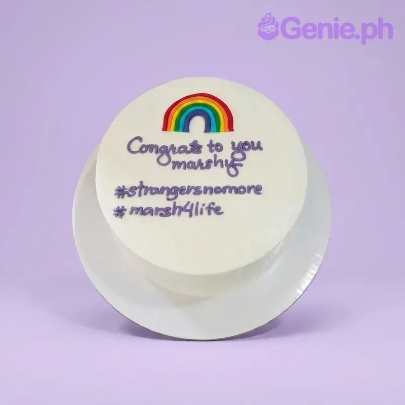 A white 1-tier cake themed around a rainbow, featuring a colorful rainbow printout and purple piped text messages. A white 1-tier cake themed around a rainbow, featuring a colorful rainbow printout and purple piped text messages.