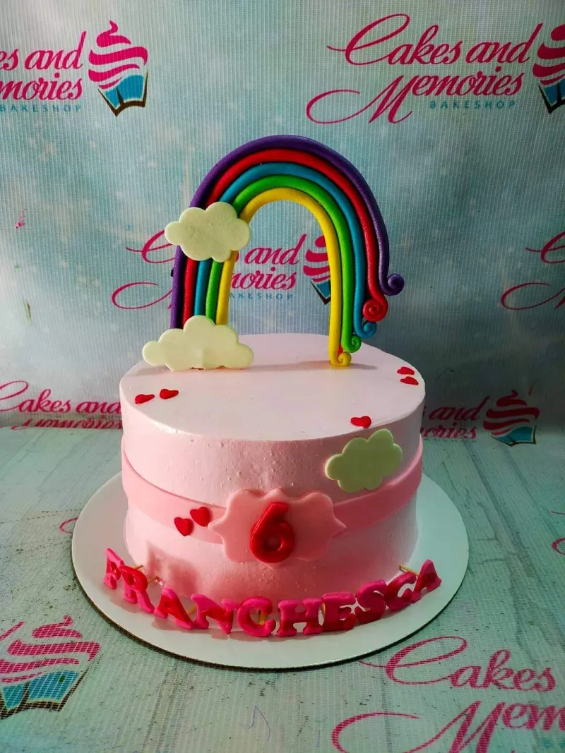 A pink and white 1 Tier cake themed Rainbow Birthday, featuring a multi-colored rainbow topper, clouds, and hearts. A pink and white 1 Tier cake themed Rainbow Birthday, featuring a multi-colored rainbow topper, clouds, and hearts.