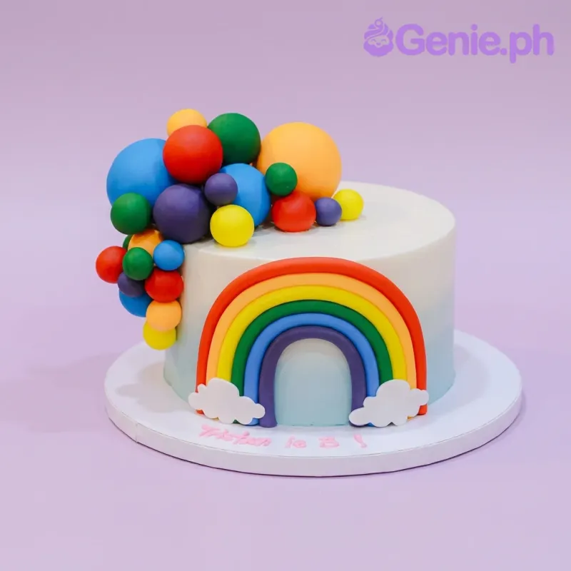 A white and light blue gradient 1-tier cake themed Rainbow Sphere, featuring a large 3D fondant rainbow and colorful fondant spheres. A white and light blue gradient 1-tier cake themed Rainbow Sphere, featuring a large 3D fondant rainbow and colorful fondant spheres.