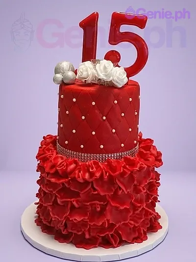 A red and white 2-tier 15th birthday cake, featuring a red number 15 topper, ruffled icing, and quilted pattern. A red and white 2-tier 15th birthday cake, featuring a red number 15 topper, ruffled icing, and quilted pattern.