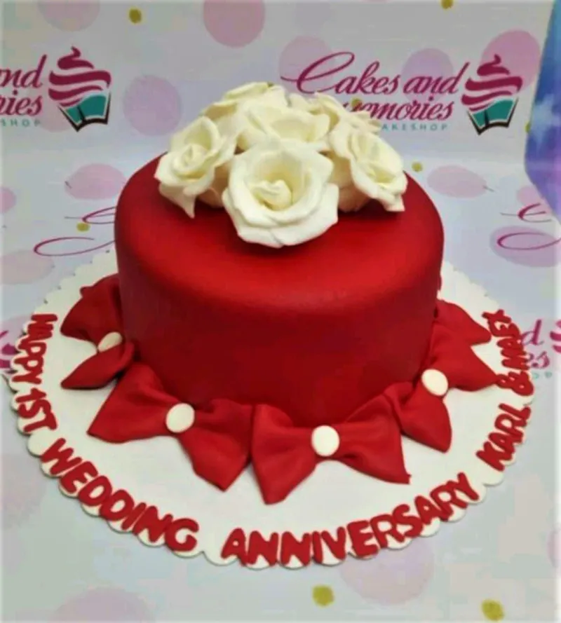 A red and white 1 Tier Fondant cake themed around Anniversary, featuring white gumpaste roses and red bows with white centers. A red and white 1 Tier Fondant cake themed around Anniversary, featuring white gumpaste roses and red bows with white centers.