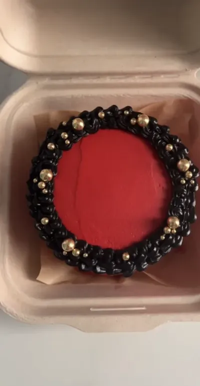 Vibrant red bento cake with smooth soft icing, black piped top border, and scattered gold sugar pearls Vibrant red bento cake with smooth soft icing, black piped top border, and scattered gold sugar pearls