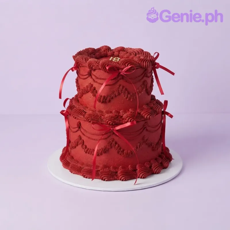 Dark red two-tier soft icing cake with piped shell borders, red satin ribbon bows, and a gold number eighteen topper Dark red two-tier soft icing cake with piped shell borders, red satin ribbon bows, and a gold number eighteen topper