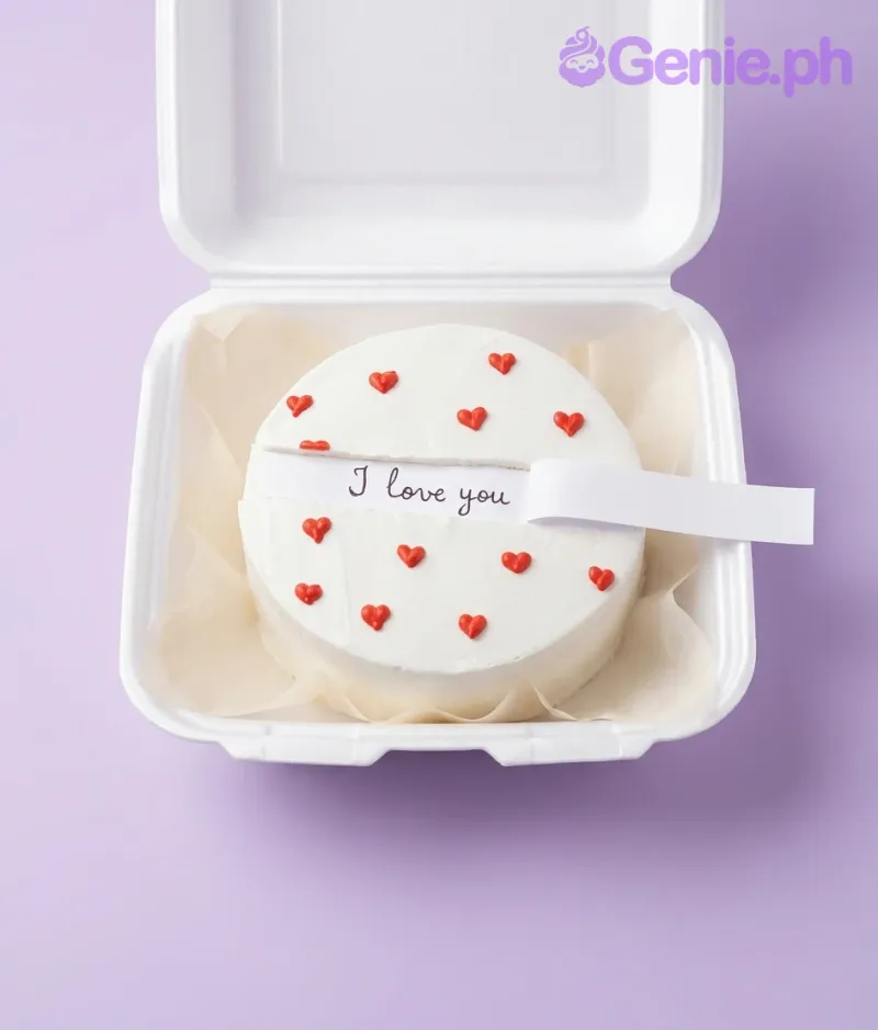 A white bento cake themed around Red Minimalist, featuring a hidden pull-out message strip and piped red icing hearts. A white bento cake themed around Red Minimalist, featuring a hidden pull-out message strip and piped red icing hearts.
