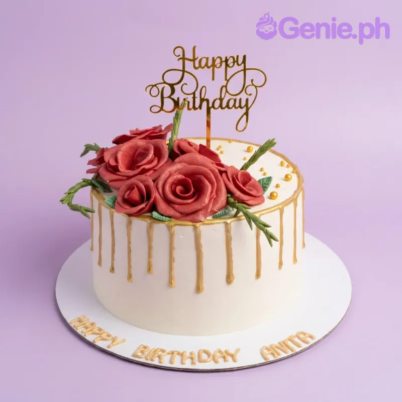 A white 1-tier cake with red gumpaste roses, a gold 'Happy Birthday' topper, gold drip, green leaves, and gold beads. A white 1-tier cake with red gumpaste roses, a gold 'Happy Birthday' topper, gold drip, green leaves, and gold beads.
