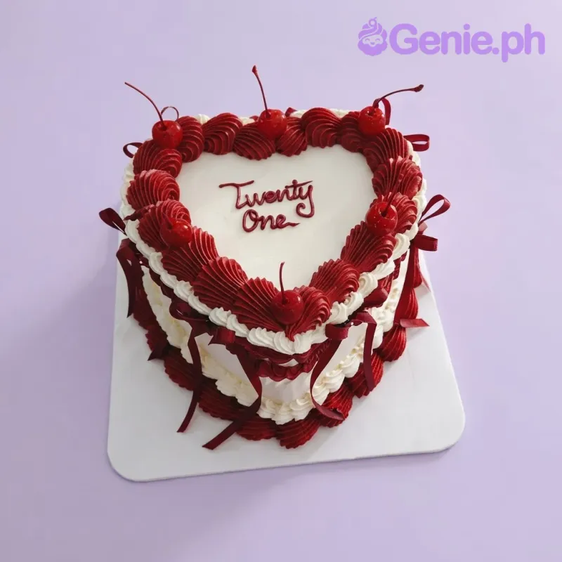 White heart cake with smooth soft icing, dark red vintage buttercream borders, cherries, and satin ribbon bows