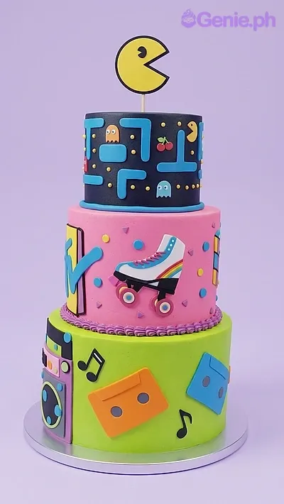 A multicolored 3-tier fondant cake with a Retro 80s 90s theme, featuring Pac-Man, MTV logo, roller skates, and cassette tapes. A multicolored 3-tier fondant cake with a Retro 80s 90s theme, featuring Pac-Man, MTV logo, roller skates, and cassette tapes.
