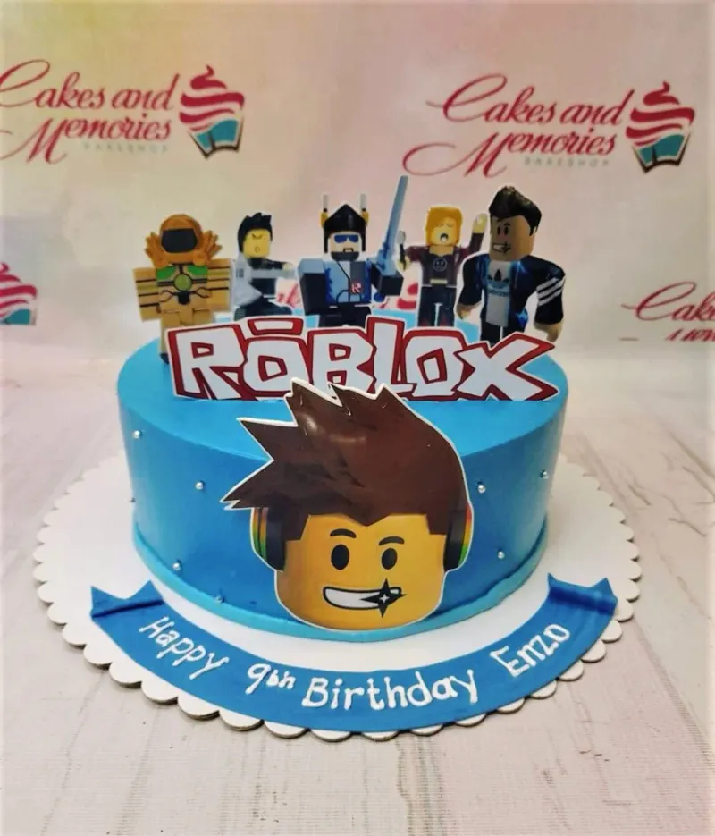 A blue and white 1-tier cake themed around Roblox, featuring Roblox character printouts and silver dragees. A blue and white 1-tier cake themed around Roblox, featuring Roblox character printouts and silver dragees.