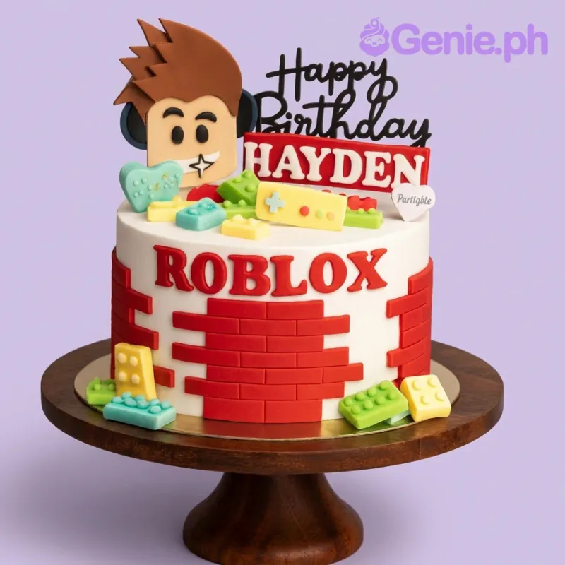 A 1 Tier Fondant Roblox cake, featuring a 3D character head, red brick panels, and colorful building blocks. A 1 Tier Fondant Roblox cake, featuring a 3D character head, red brick panels, and colorful building blocks.