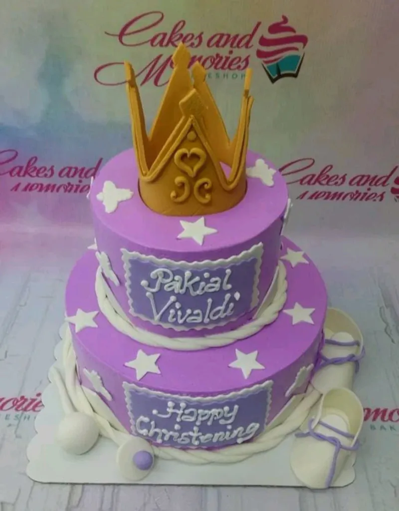 Two-tier purple fondant christening cake with a large gold crown topper, white stars, and baby shoes. Two-tier purple fondant christening cake with a large gold crown topper, white stars, and baby shoes.