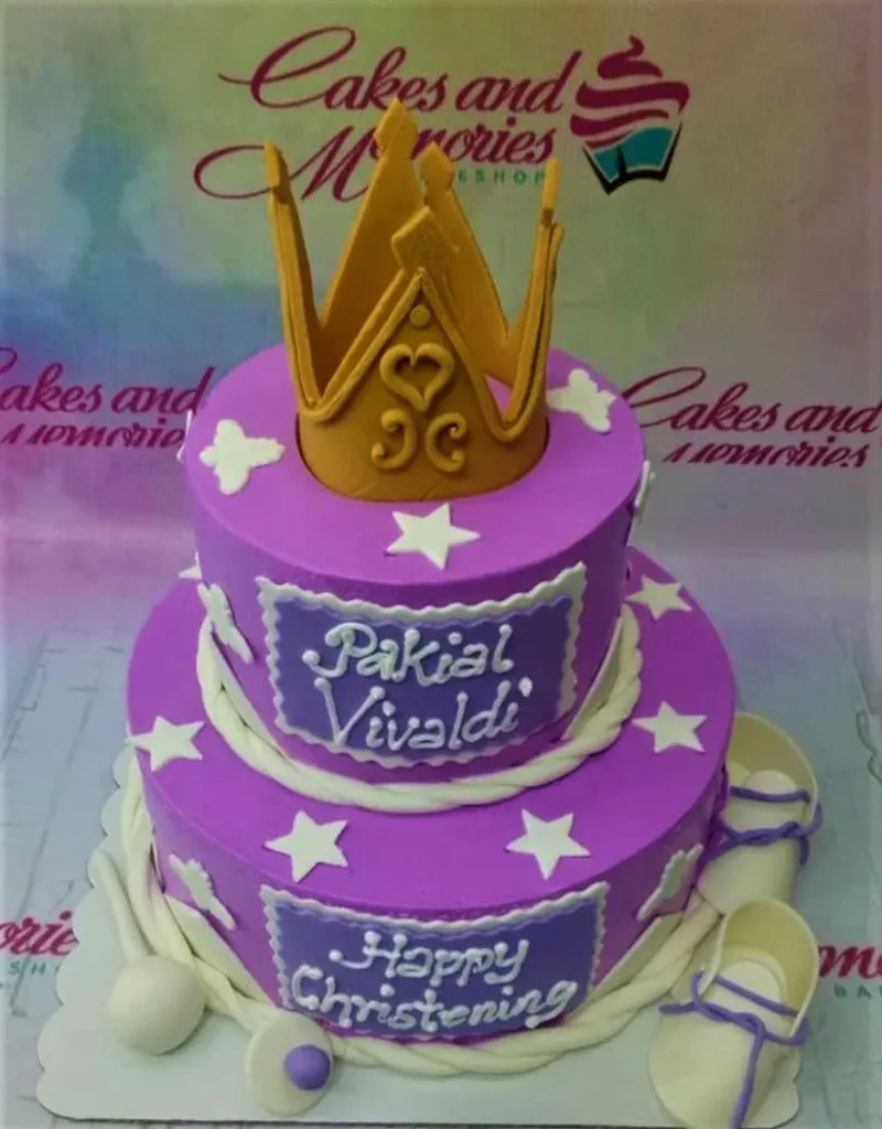 Two-tier purple fondant christening cake with a large gold crown topper, white stars, and baby shoes. Two-tier purple fondant christening cake with a large gold crown topper, white stars, and baby shoes.