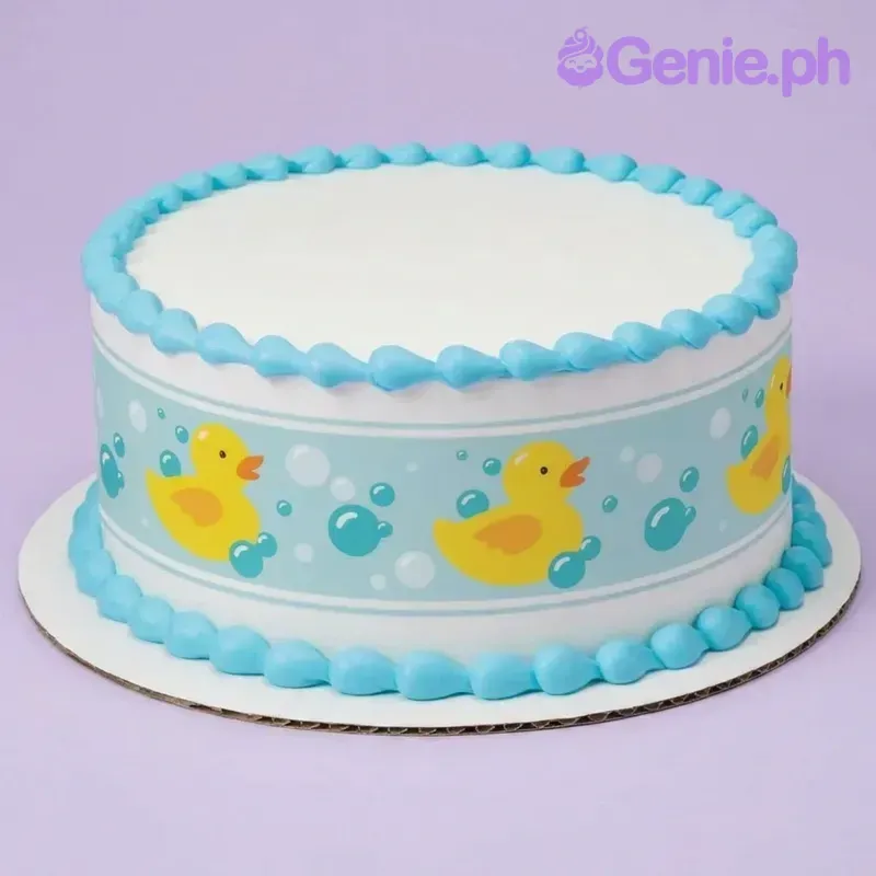 A white and blue round 1-tier Rubber Duck cake, featuring an edible side wrap with yellow ducks and blue teardrop icing borders. A white and blue round 1-tier Rubber Duck cake, featuring an edible side wrap with yellow ducks and blue teardrop icing borders.