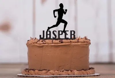 Brown chocolate cake with piped icing borders, chocolate sprinkles, and a black runner silhouette name topper Brown chocolate cake with piped icing borders, chocolate sprinkles, and a black runner silhouette name topper