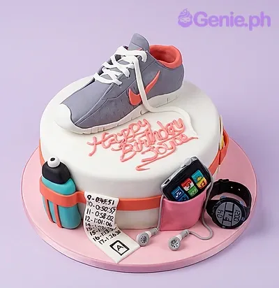 White fondant cake with a sculpted sneaker topper, race bib, water bottle, and sports watch decorations. White fondant cake with a sculpted sneaker topper, race bib, water bottle, and sports watch decorations.