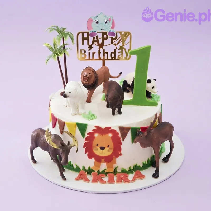 A white and gold 1-tier Safari Animal cake, with animal toys, a 'Happy Birthday' topper, and palm trees. A white and gold 1-tier Safari Animal cake, with animal toys, a 'Happy Birthday' topper, and palm trees.