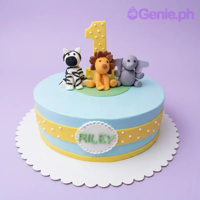 A light blue 1-tier Safari First Birthday cake with fondant lion, zebra, purple elephant, yellow number one, and 'RILEY' text. A light blue 1-tier Safari First Birthday cake with fondant lion, zebra, purple elephant, yellow number one, and 'RILEY' text.
