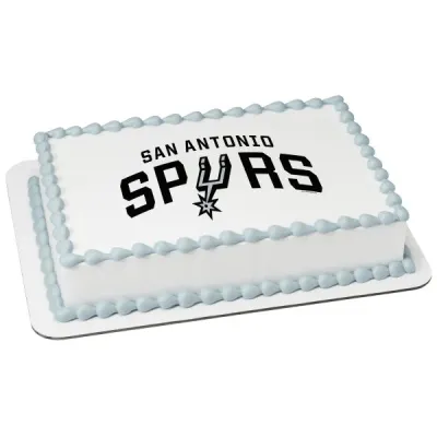 A white rectangular San Antonio Spurs basketball cake with a printed team logo and light blue piped icing borders. A white rectangular San Antonio Spurs basketball cake with a printed team logo and light blue piped icing borders.