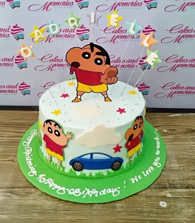 Shin-chan themed birthday cake with light blue icing, white clouds, and colorful star decorations on a green base board. Shin-chan themed birthday cake with light blue icing, white clouds, and colorful star decorations on a green base board.