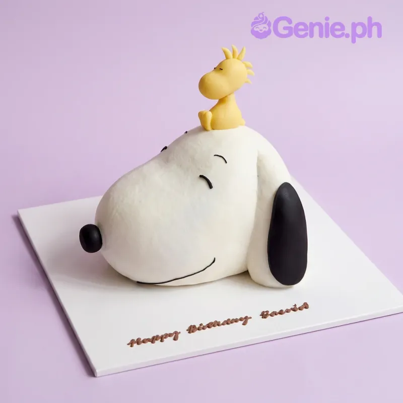 White Snoopy shaped cake with a yellow Woodstock figure on top and Happy Birthday message on the board White Snoopy shaped cake with a yellow Woodstock figure on top and Happy Birthday message on the board