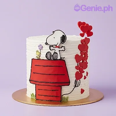 White 1-tier cake with a Snoopy and doghouse printout and red heart accents White 1-tier cake with a Snoopy and doghouse printout and red heart accents