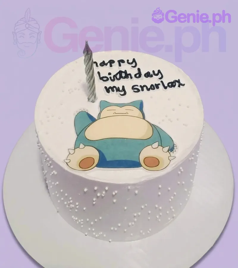 A white 1 Tier cake themed around Snorlax Pokemon, featuring a sleeping Snorlax printout topper, silver candle, white pearl sprinkles, and a birthday message. A white 1 Tier cake themed around Snorlax Pokemon, featuring a sleeping Snorlax printout topper, silver candle, white pearl sprinkles, and a birthday message.