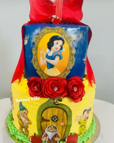 Blue and yellow two tier birthday cake with Snow White printout and red satin ribbon Blue and yellow two tier birthday cake with Snow White printout and red satin ribbon