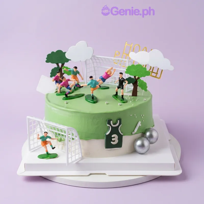 Light green 1-tier cake with soccer player figurines, a goal net, and tree and cloud cutouts Light green 1-tier cake with soccer player figurines, a goal net, and tree and cloud cutouts