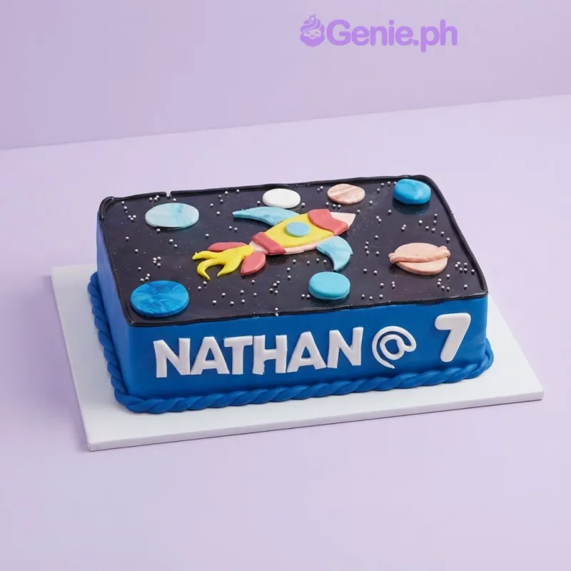 A blue and black rectangle cake themed around Space, featuring a fondant rocket ship, planets, and silver dragees stars. A blue and black rectangle cake themed around Space, featuring a fondant rocket ship, planets, and silver dragees stars.