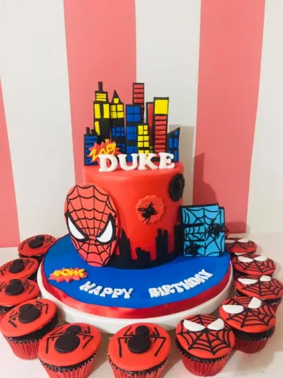 Vibrant red and blue 1-tier fondant cake with a Spiderman face plaque, cityscape buildings topper, and spider web accents Vibrant red and blue 1-tier fondant cake with a Spiderman face plaque, cityscape buildings topper, and spider web accents