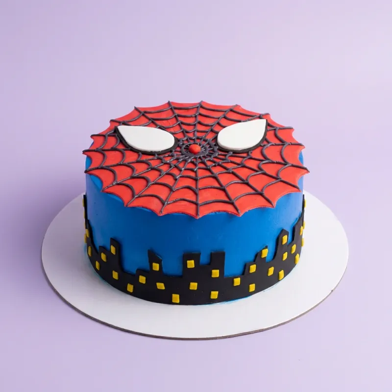 A blue, red, and black 1 Tier cake themed around Spiderman, featuring a red spiderweb panel with white eyes and a black city skyline. A blue, red, and black 1 Tier cake themed around Spiderman, featuring a red spiderweb panel with white eyes and a black city skyline.