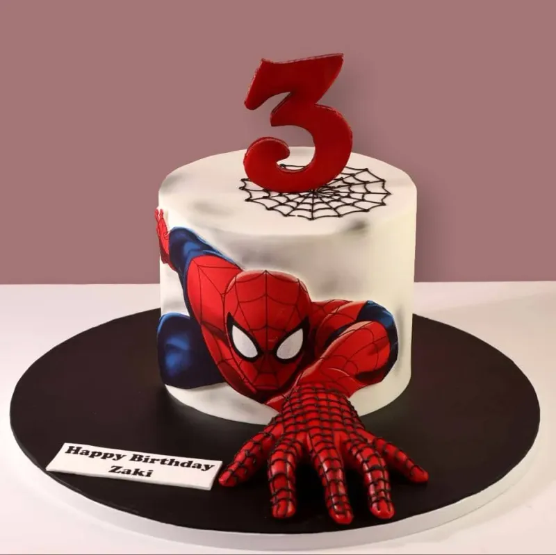 White 1-tier soft icing cake with a Spiderman printout, a red number three topper, and a black piped spider web White 1-tier soft icing cake with a Spiderman printout, a red number three topper, and a black piped spider web