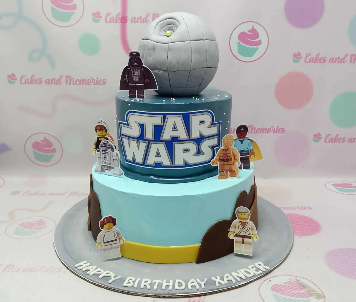 A blue two-tier Star Wars Lego cake, featuring a Death Star and Lego characters. A blue two-tier Star Wars Lego cake, featuring a Death Star and Lego characters.