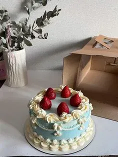 Light blue 1-tier cake with soft icing, fresh strawberry toppers, and white piped borders Light blue 1-tier cake with soft icing, fresh strawberry toppers, and white piped borders
