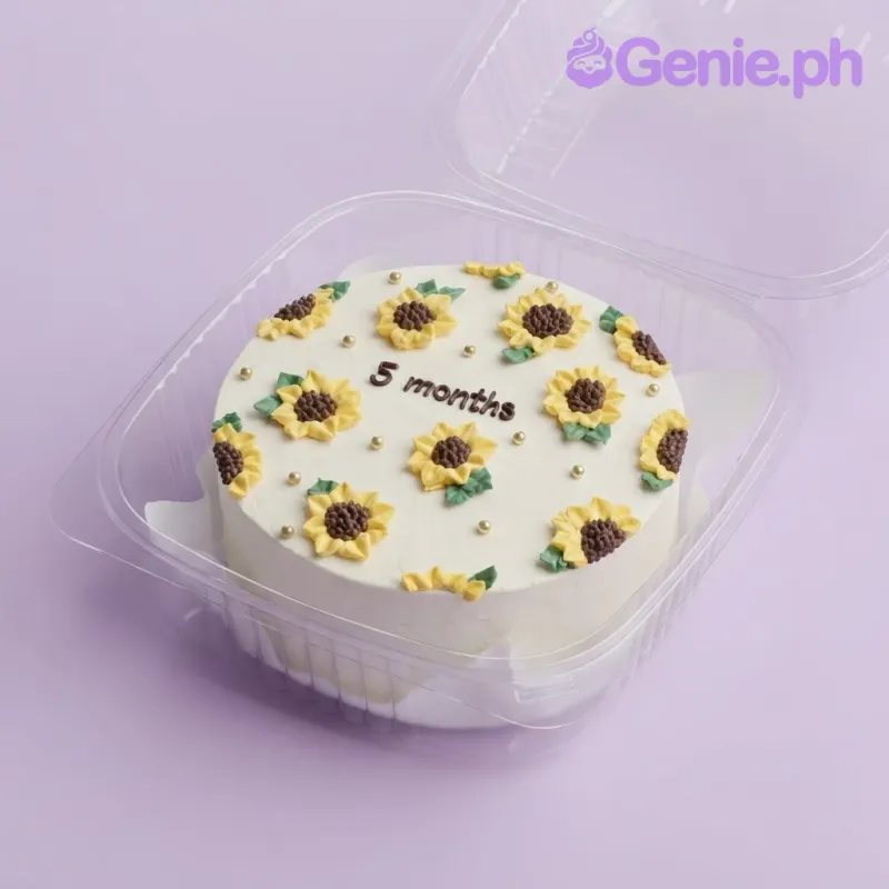 White bento cake with soft icing, piped sunflower decorations, and a black iced month message White bento cake with soft icing, piped sunflower decorations, and a black iced month message