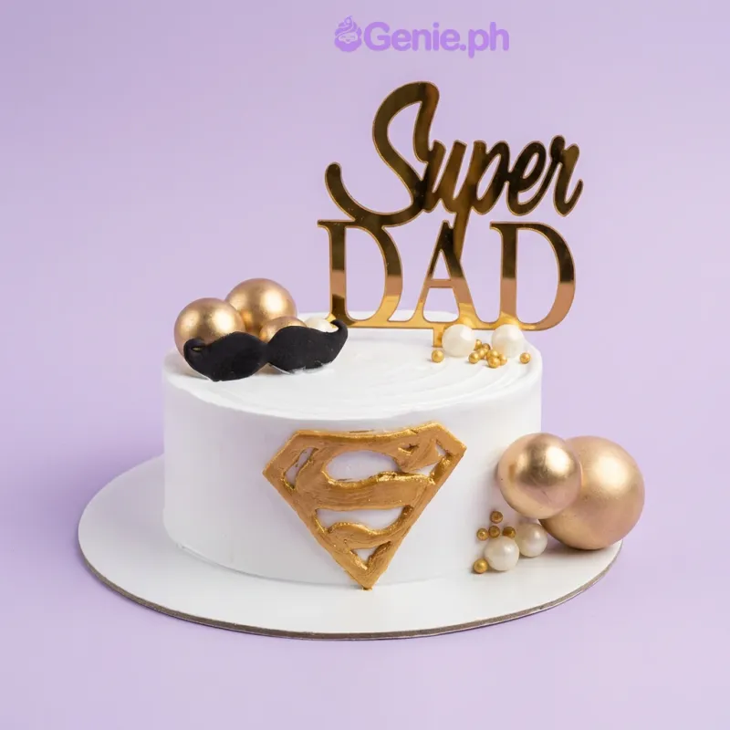 White single-tier cake with gold Super Dad topper and Superman logo White single-tier cake with gold Super Dad topper and Superman logo