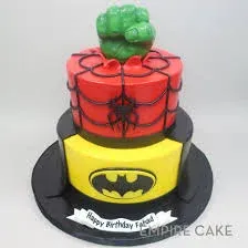 Red and yellow 2-tier fondant superhero cake with a Hulk fist topper and Batman logo panels Red and yellow 2-tier fondant superhero cake with a Hulk fist topper and Batman logo panels