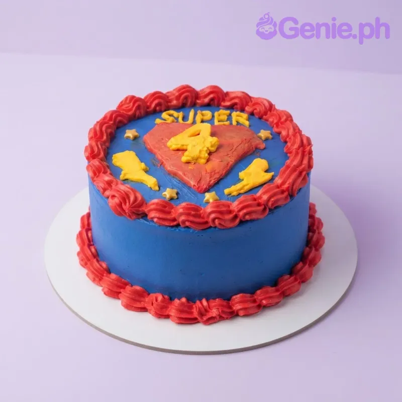 Blue 1-tier cake with smooth soft icing, a Superman shield topper, and red piped borders Blue 1-tier cake with smooth soft icing, a Superman shield topper, and red piped borders