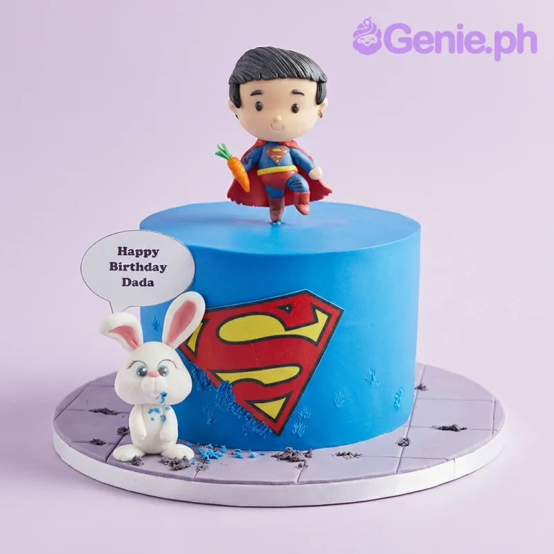 Blue Superman themed cake with a fondant superhero figure holding a carrot and a white bunny figure on a grey tiled base. Blue Superman themed cake with a fondant superhero figure holding a carrot and a white bunny figure on a grey tiled base.