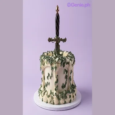 White single-tier cake with green vines and a large sword topper White single-tier cake with green vines and a large sword topper