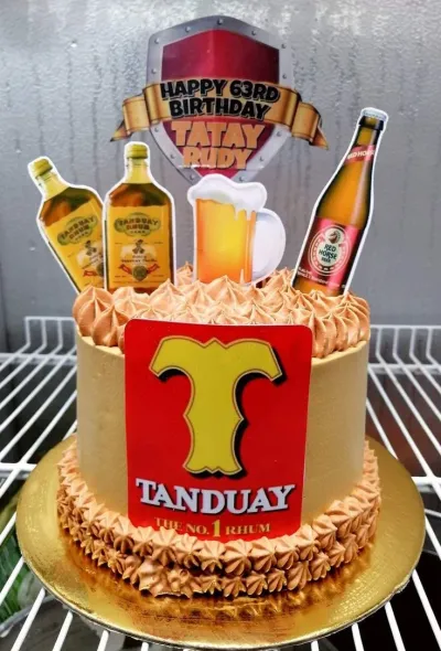 Brown 1-tier cake with soft icing, piped borders, and Tanduay-themed printout toppers including bottles and a birthday banner Brown 1-tier cake with soft icing, piped borders, and Tanduay-themed printout toppers including bottles and a birthday banner
