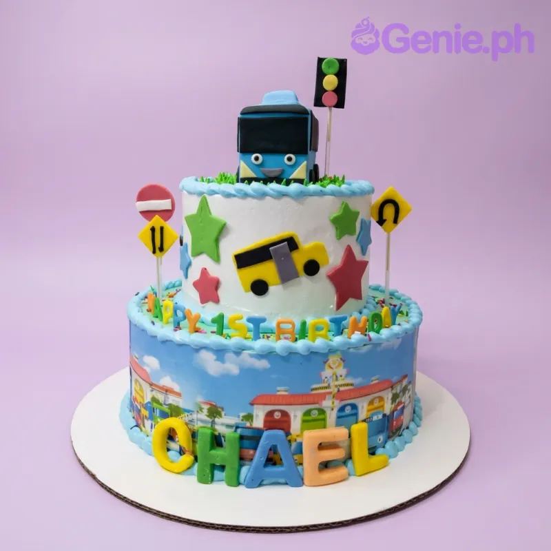 Two-tier blue and white Tayo the Little Bus themed birthday cake with fondant stars, bus toppers, and colorful name letters. Two-tier blue and white Tayo the Little Bus themed birthday cake with fondant stars, bus toppers, and colorful name letters.