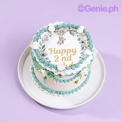 A white, blue 1-tier Teddy Bear Vintage cake with a teddy bear printout, 'Happy 2nd Birthday' text, ruffled icing.