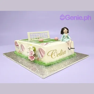 White rectangle cake with a tennis court design on top featuring a net and pink balls with a fondant girl figurine sitting on the edge White rectangle cake with a tennis court design on top featuring a net and pink balls with a fondant girl figurine sitting on the edge