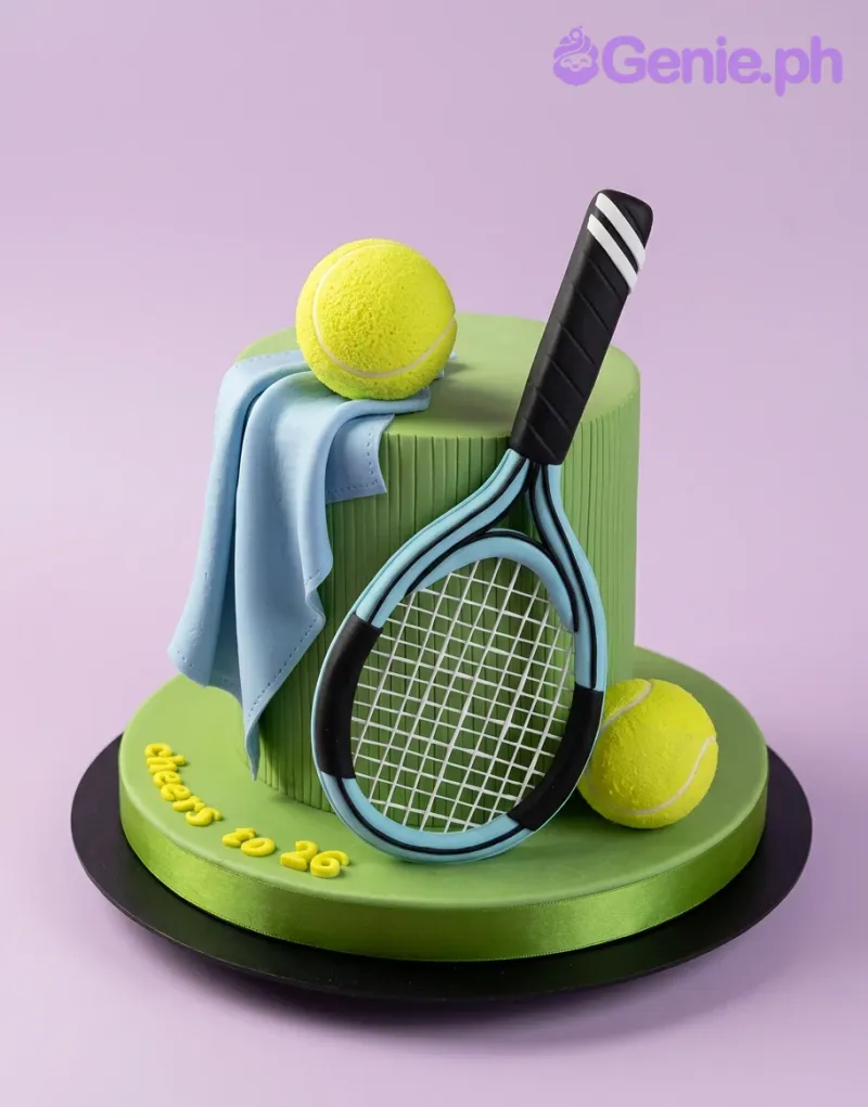 A green-blue 1 Tier Fondant Tennis cake, featuring a tennis racket, two yellow balls, and a blue towel. A green-blue 1 Tier Fondant Tennis cake, featuring a tennis racket, two yellow balls, and a blue towel.
