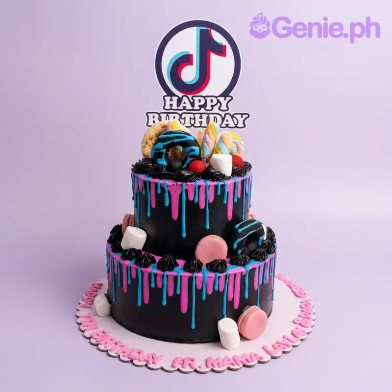 A black 2-tier TikTok cake with a logo printout, pink and blue drips, colorful donuts, marshmallows, and macarons. A black 2-tier TikTok cake with a logo printout, pink and blue drips, colorful donuts, marshmallows, and macarons.