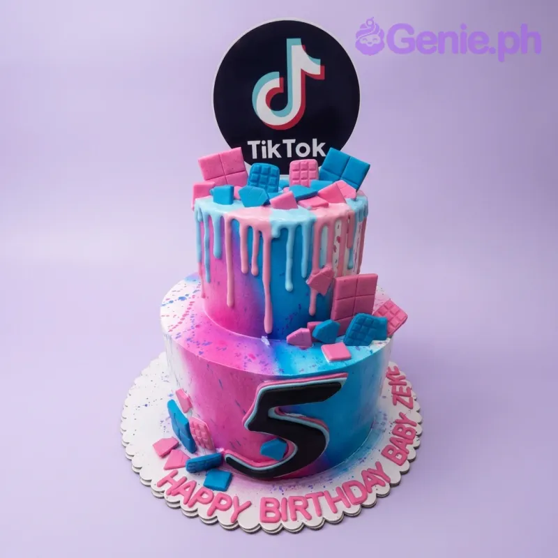 A pink and blue gradient two-tier TikTok cake, featuring a TikTok logo printout, an edible number 5, and pink and blue chocolate bars. A pink and blue gradient two-tier TikTok cake, featuring a TikTok logo printout, an edible number 5, and pink and blue chocolate bars.