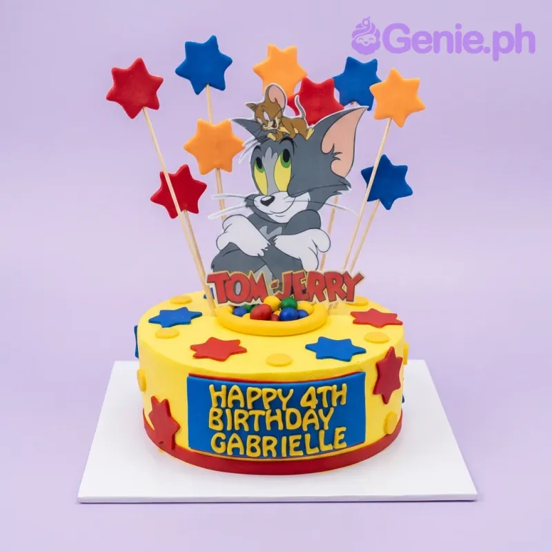 Yellow Tom and Jerry birthday cake with blue and red fondant stars and a large character printout topper. Yellow Tom and Jerry birthday cake with blue and red fondant stars and a large character printout topper.