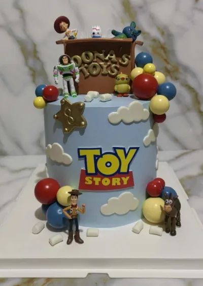 Light blue 1-tier birthday cake with soft icing, Toy Story logo, character figurines, and colorful plastic spheres Light blue 1-tier birthday cake with soft icing, Toy Story logo, character figurines, and colorful plastic spheres
